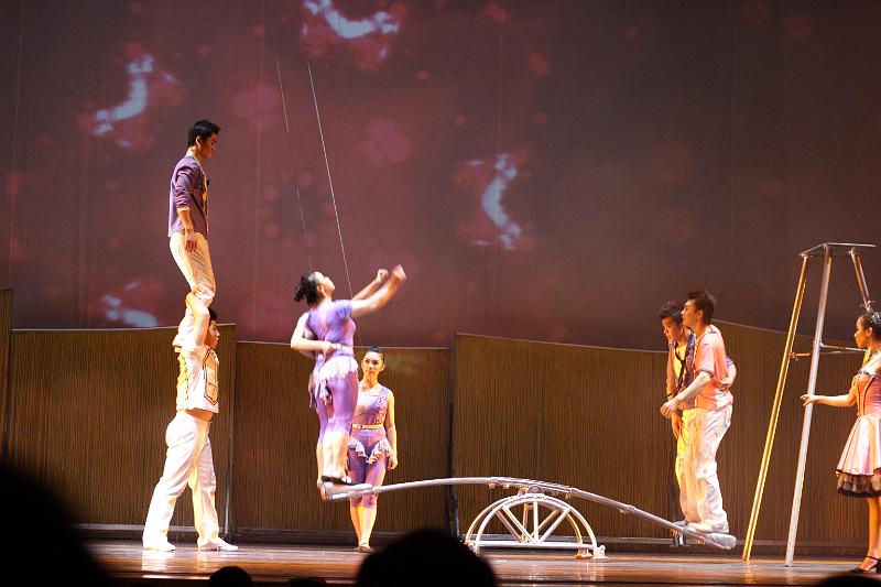 CRW_5630.JPG - After our first dinner in Shanghai, we attended a performance of Chinese acrobats.  These people were incredible!    Note that there are two girls about to be launched to the shoulder of the top guy at the left.  The acrobats are secured by safety wires.  Wouldn't you?