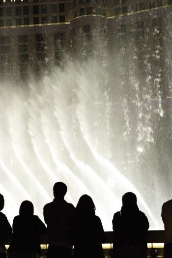 CRW_3964.JPG - Crowds gather to watch the Bellagio fountains at night.  There is a different show every 15 minutes.  Here, the streams of water are undulating to fit the music.  You can see part of the front of Bellagio in the background.  It was bright enough that this shot was done hand held.